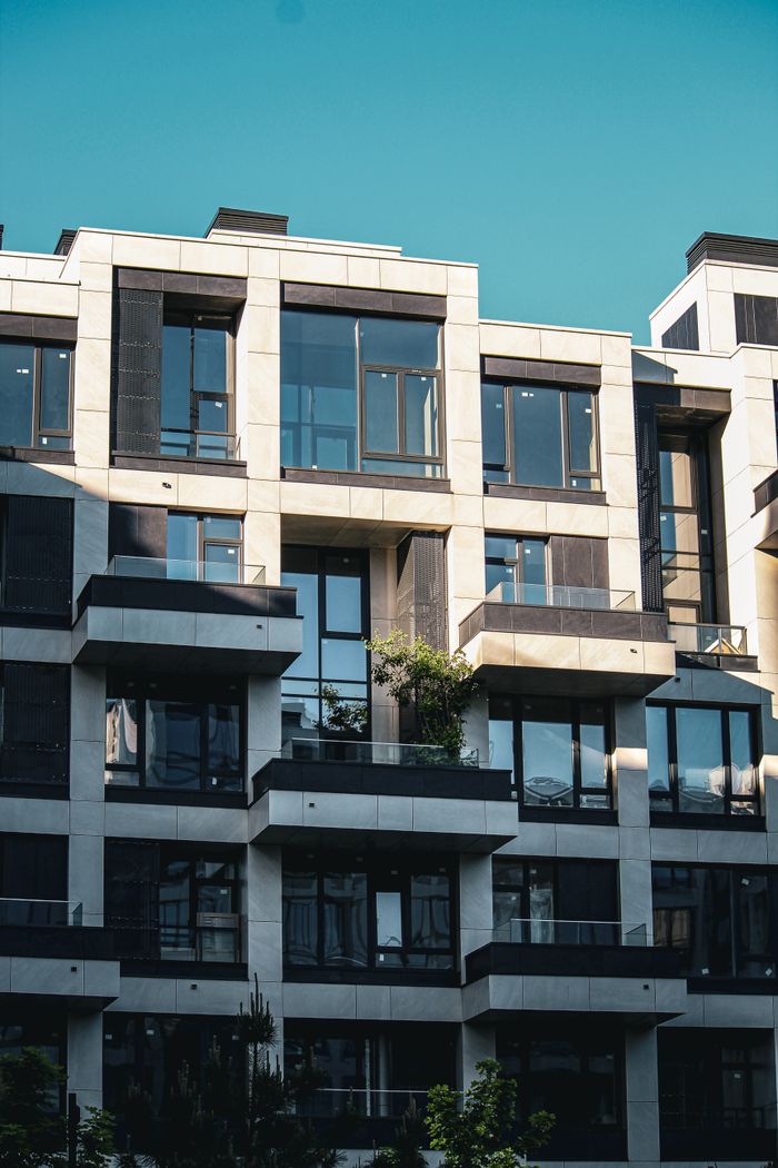 our-experience Contemporary apartment building facade with balconies and clear blue sky.